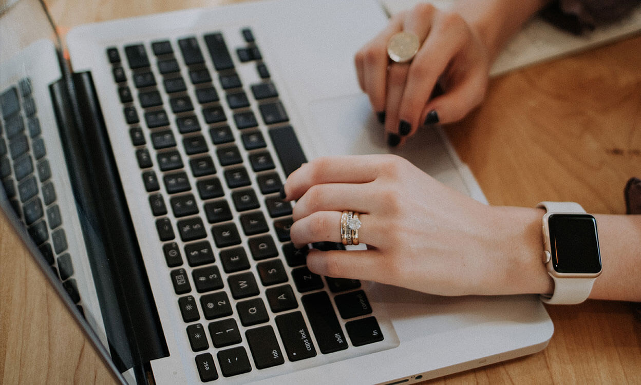 Hands typing on a laptop keyboard.