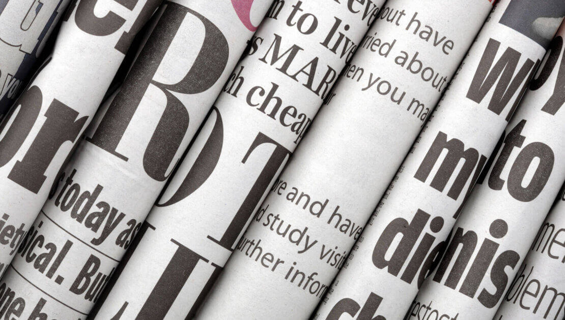 Rolled newspapers with bold text headlines.