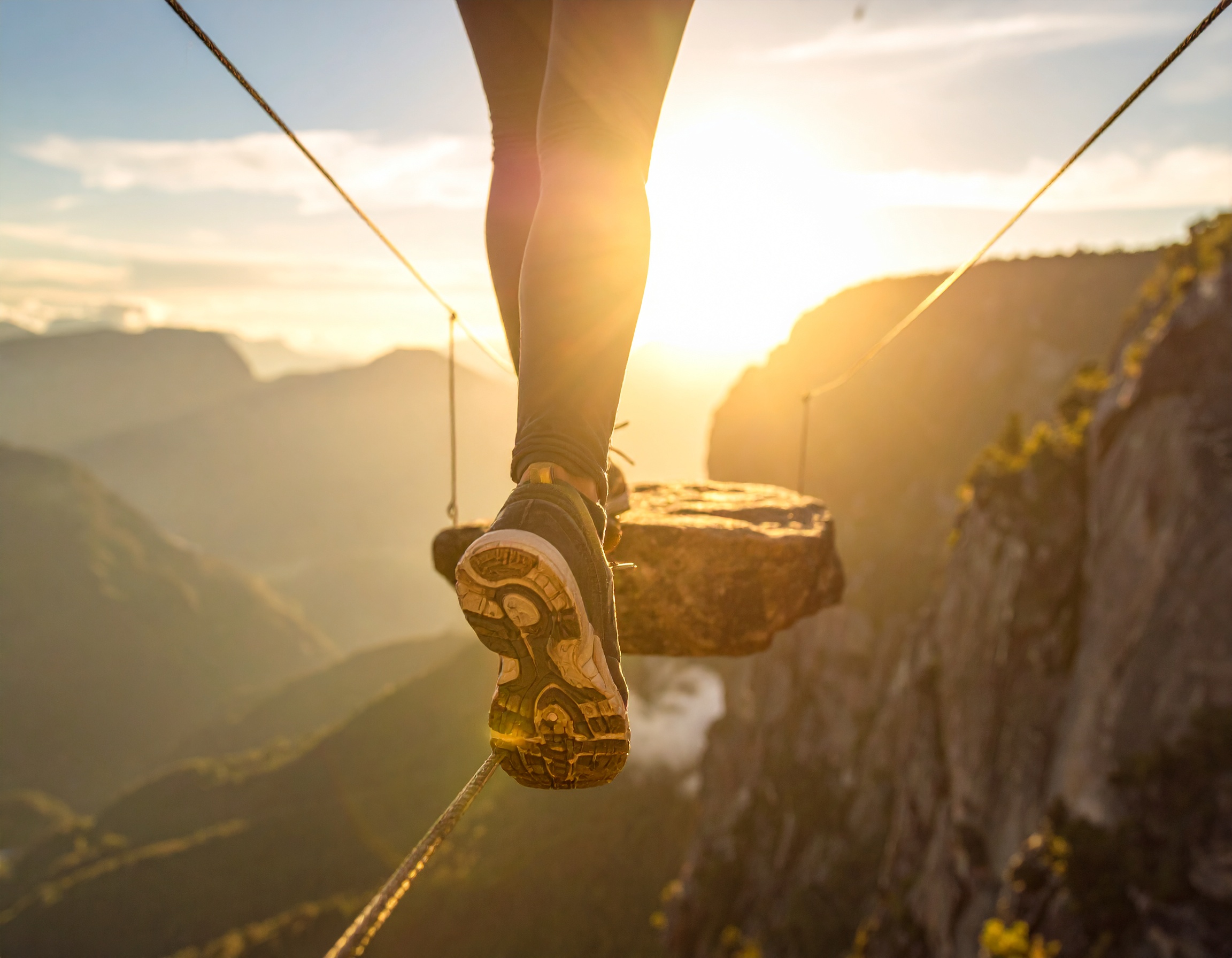 Person walking on tightrope at sunset.
