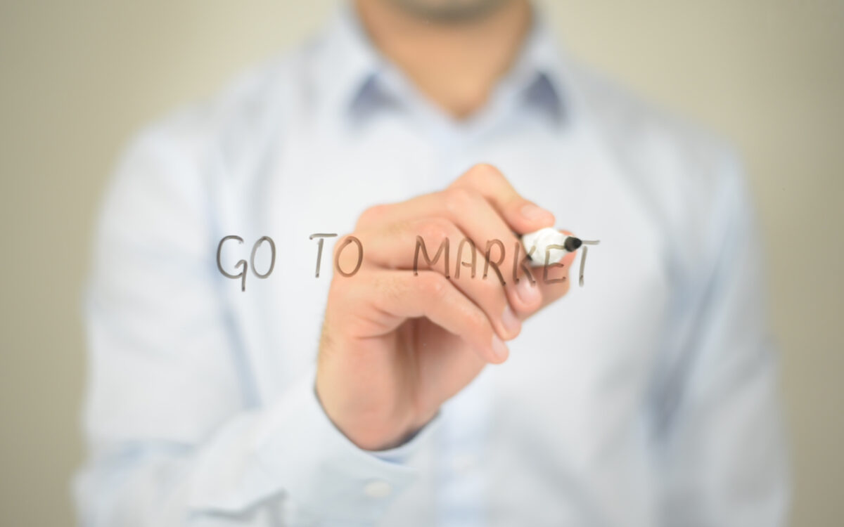 Person writing "Go to Market" on glass.