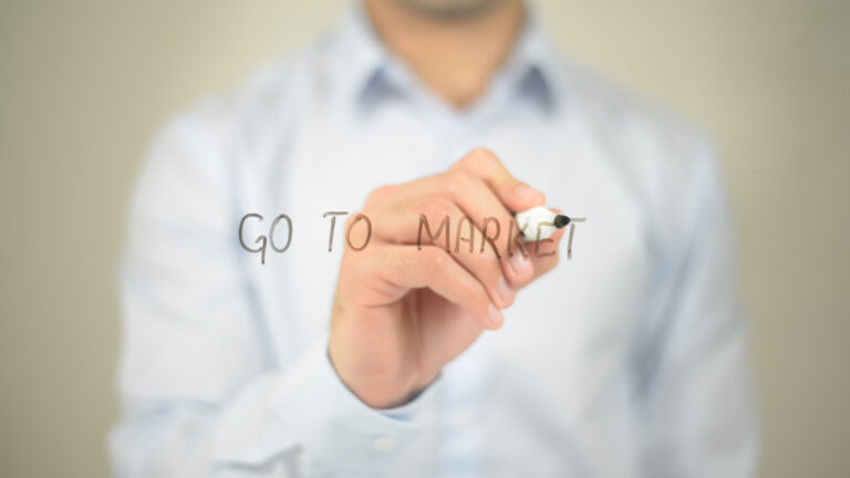 Person writing "Go to Market" on glass.