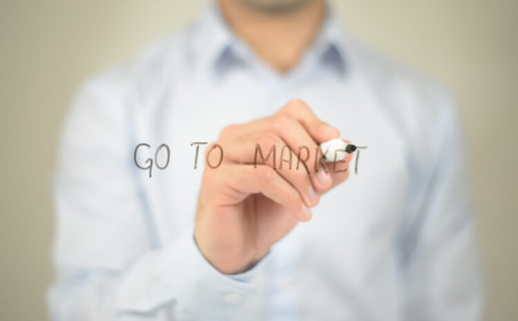 Person writing "Go to Market" on glass.
