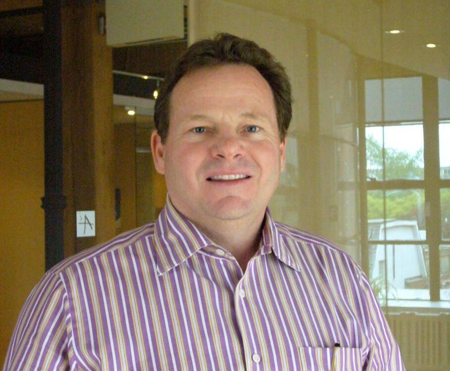 Man in striped shirt indoors, smiling.