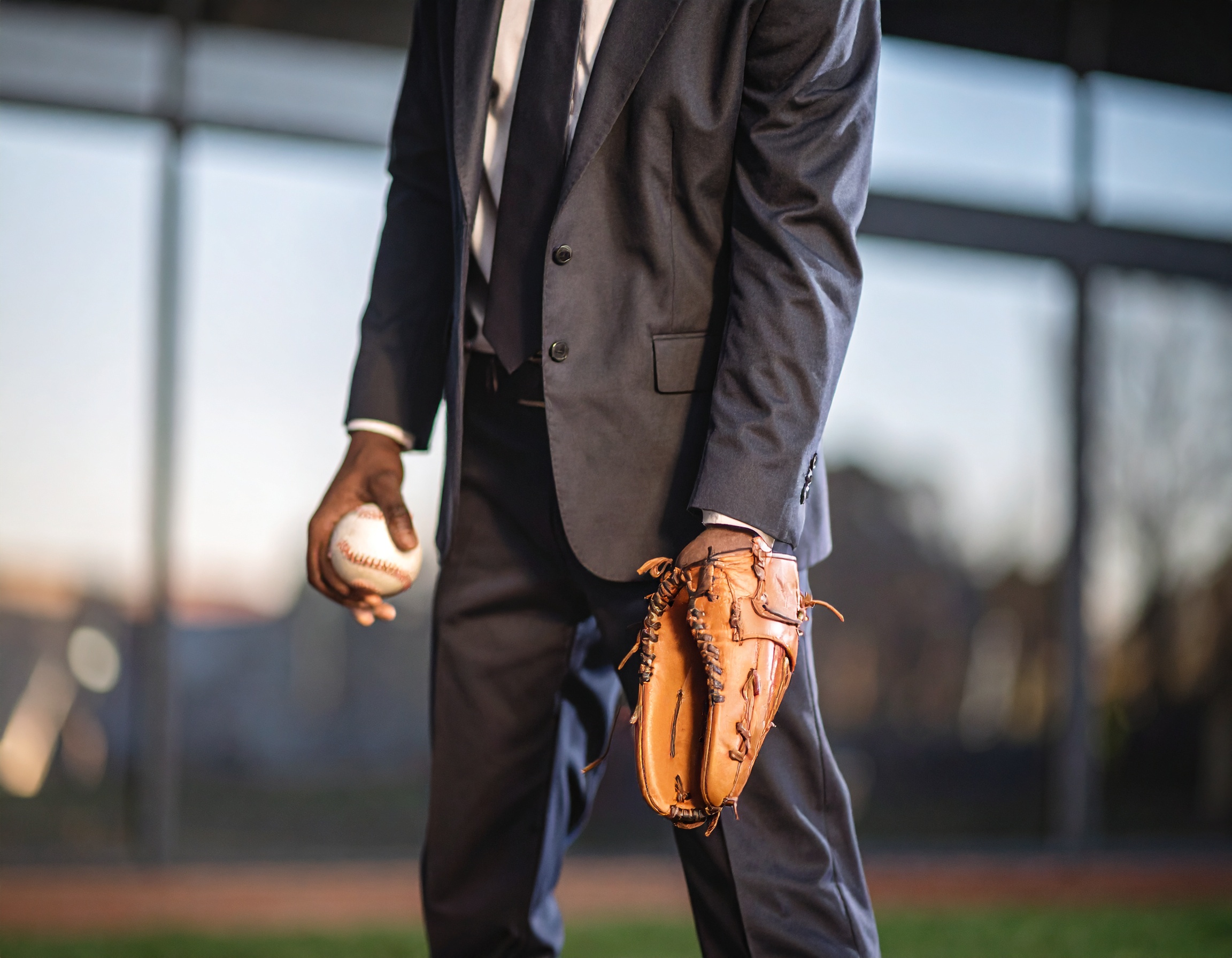 Man in suit holding baseball and glove.