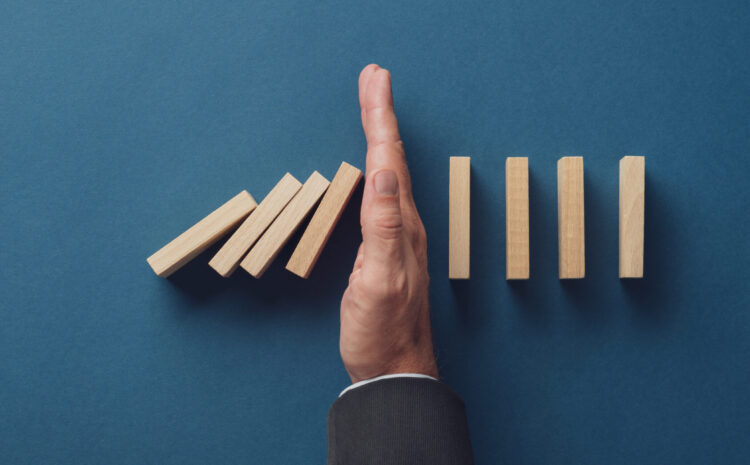 Hand stopping falling wooden dominoes.