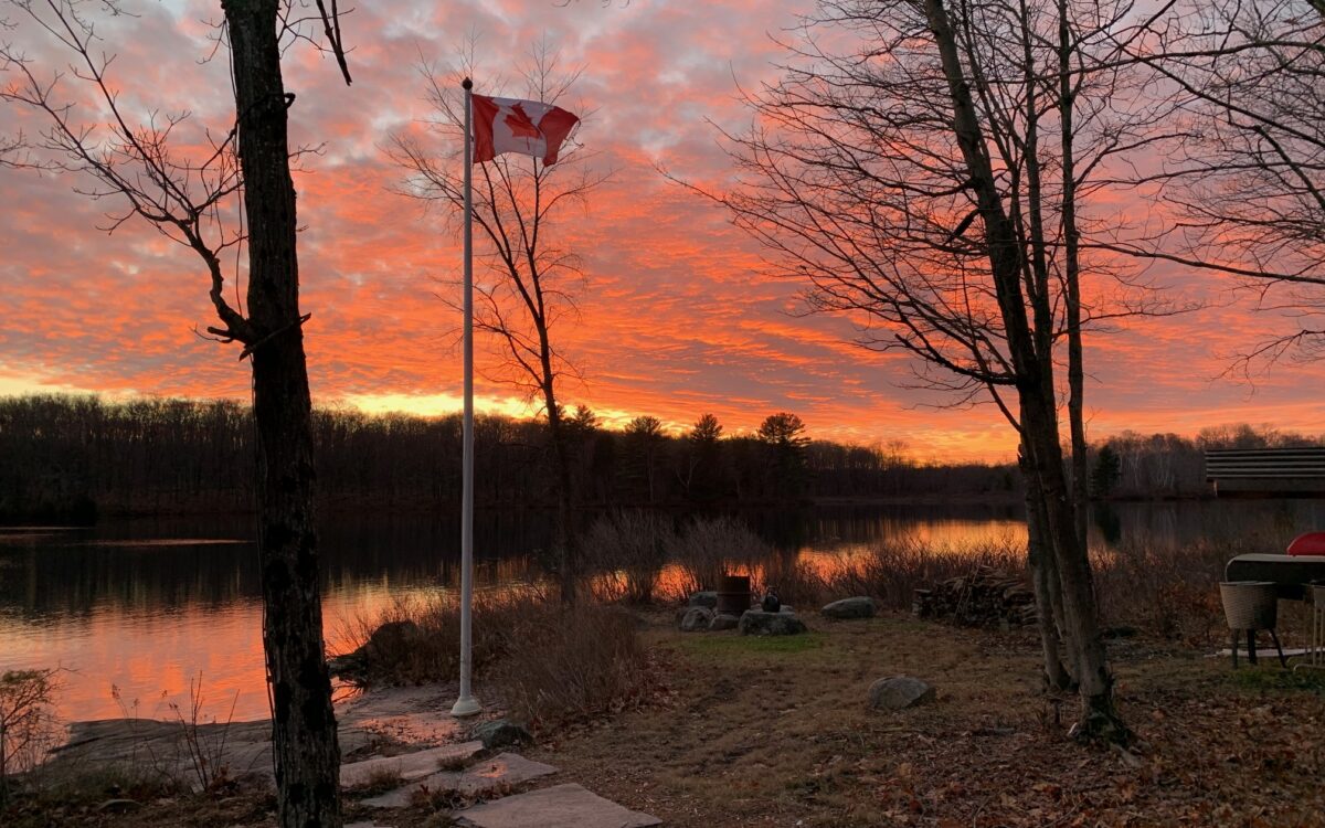 Sunrise over lake with Canadian flag.