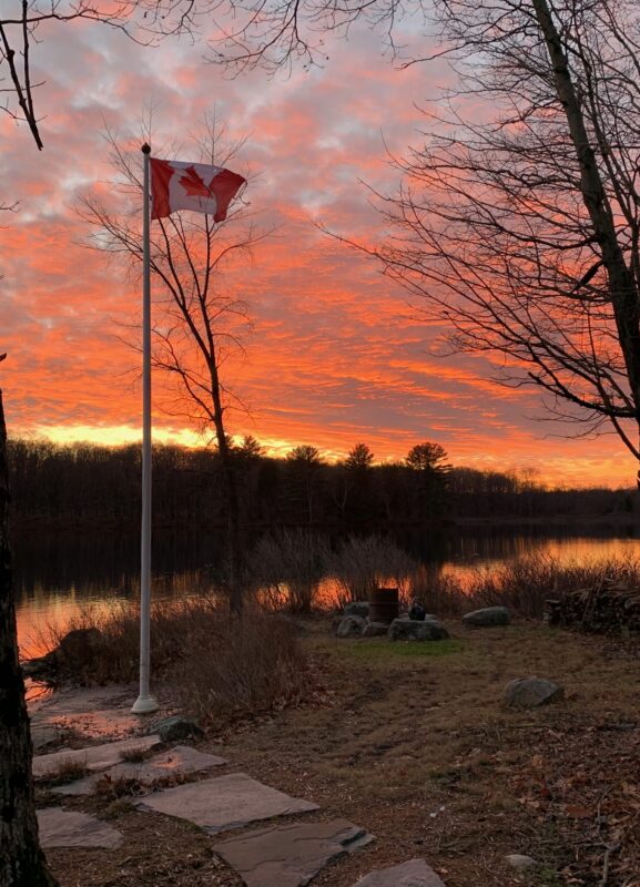 Sunrise over lake with Canadian flag.